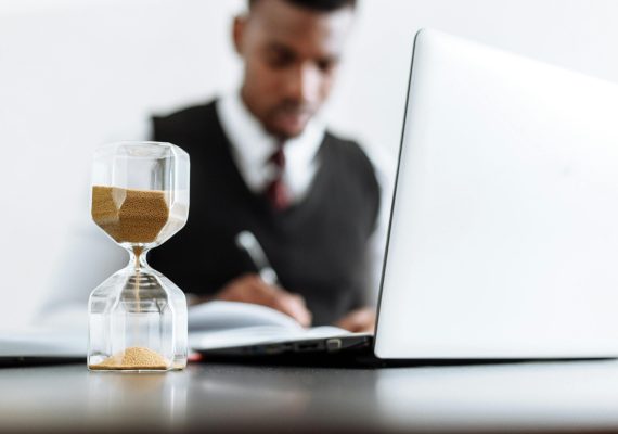 pexels-photo-5060979-5060979 Businessman at desk with hourglass indicating time management and daily work routine.